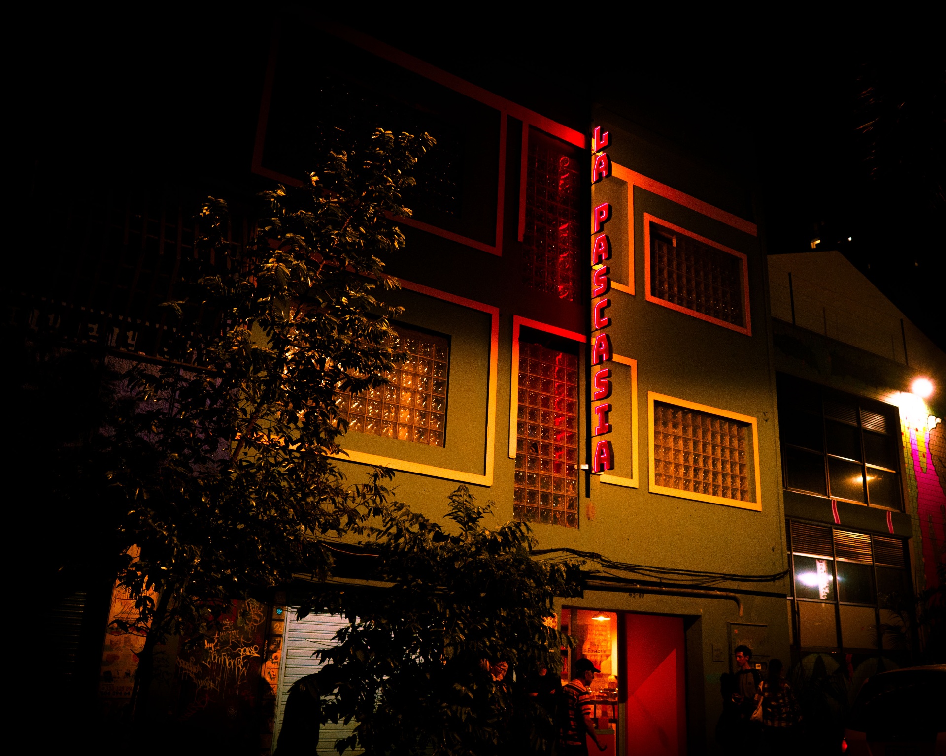 Fachada de La Pascasia de noche con letrero de neón