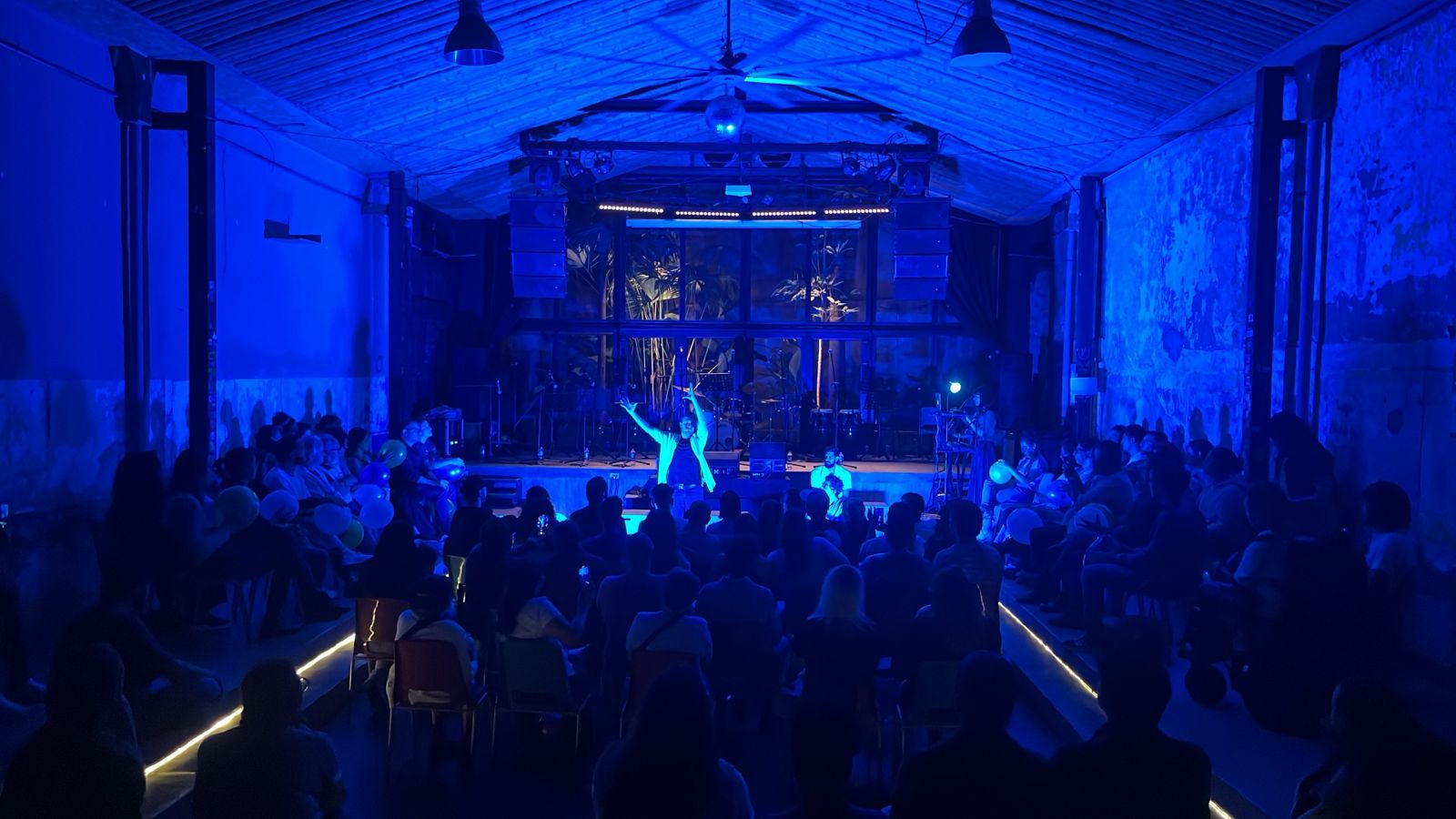 Concierto en La Pascasia con público diverso bajo iluminación azul